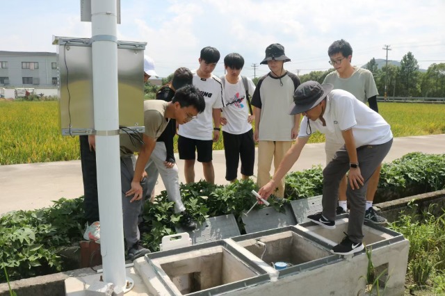 宁波财经学院“数智赋能乡村”暑期社会实践团成员在田间调试安装设备 学校供图.jpg