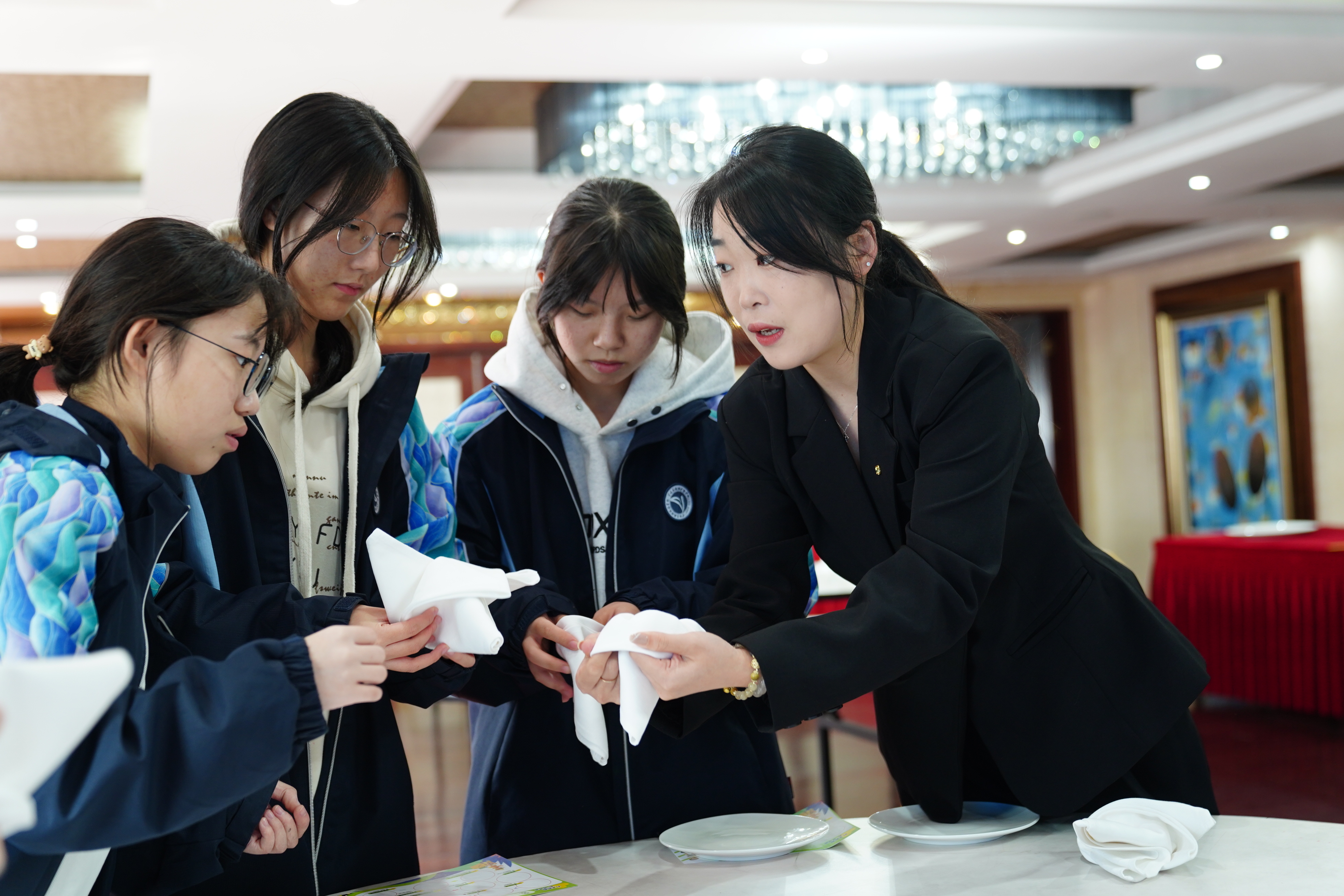 宁波东钱湖旅游学校学生在企业导师（右一）的指导下体验指尖艺术(中餐摆台)项目 胡佳 摄.jpg